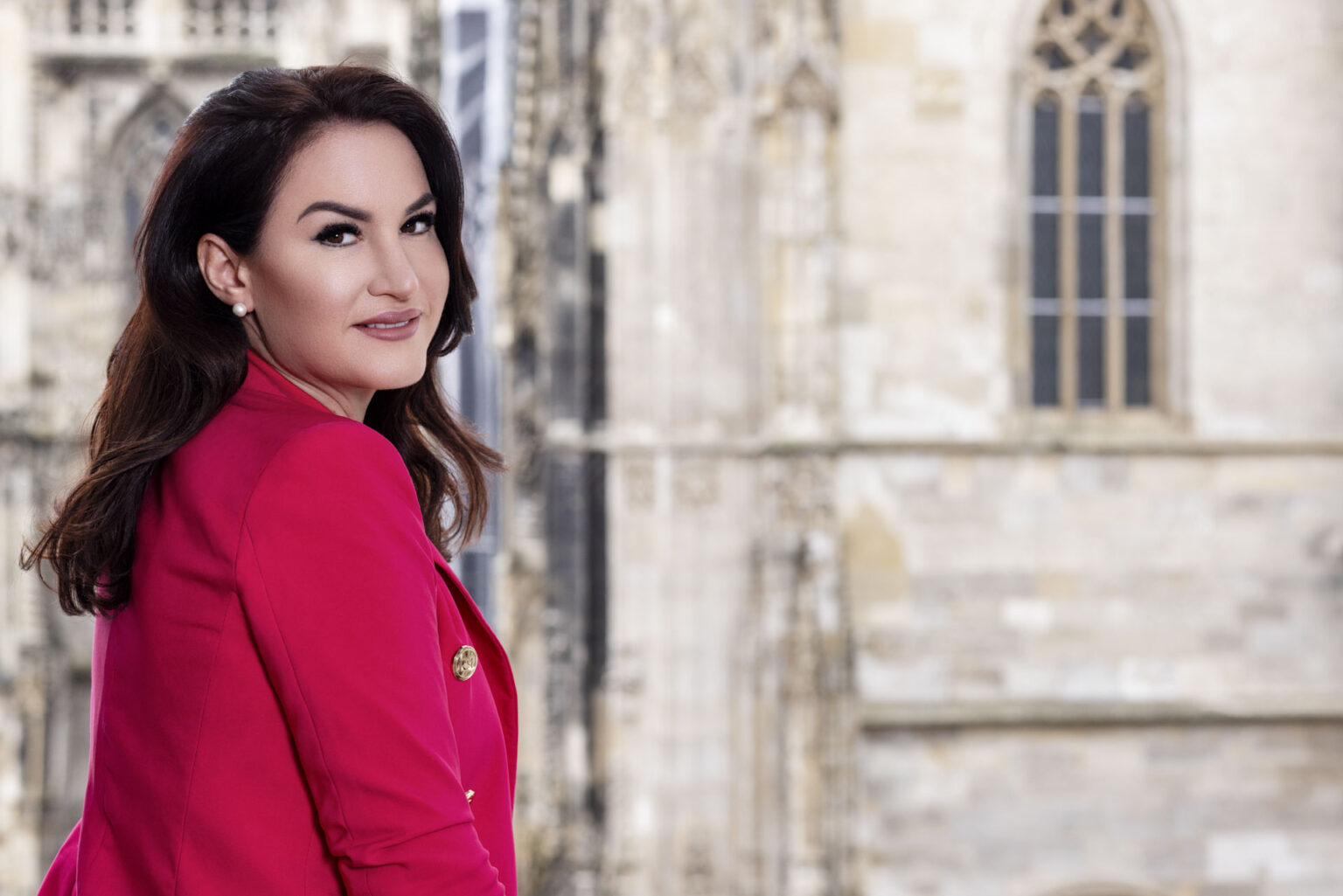 Charlotte Lenz vor einem Fenster im Büro mit pinken Blazer Charlotte Lenz vor einem Fenster im Büro mit pinken Blazer